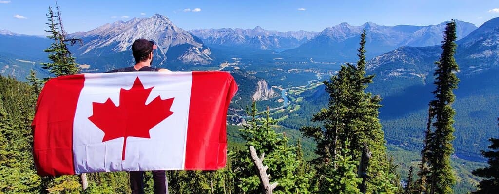 Man holding Canada flag on top of Sulphur mountain in Alberta, Canada